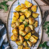 Roasted potatoes with dill and garlic on a wooden dinner table.