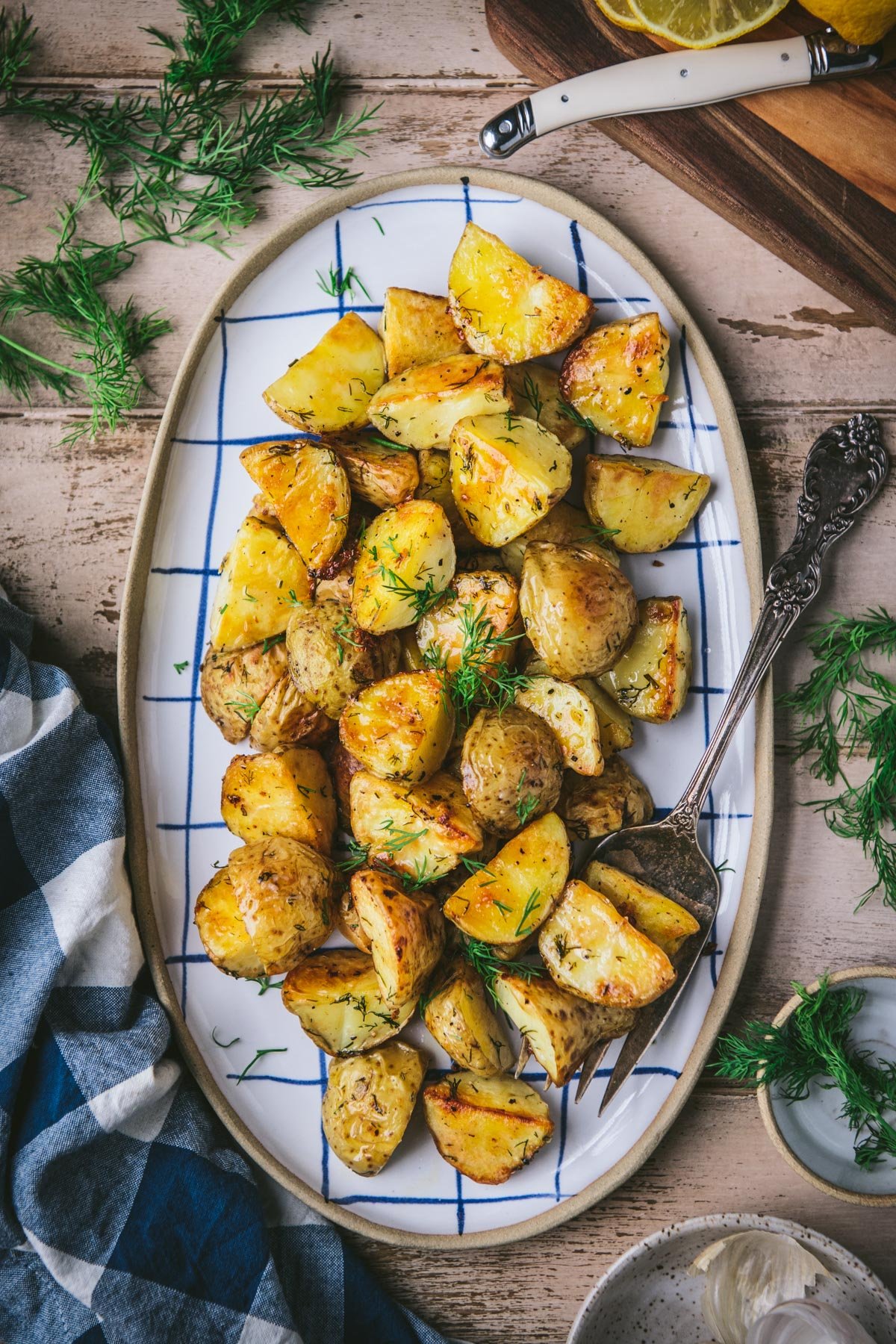 Roasted potatoes with dill and garlic on a wooden dinner table.