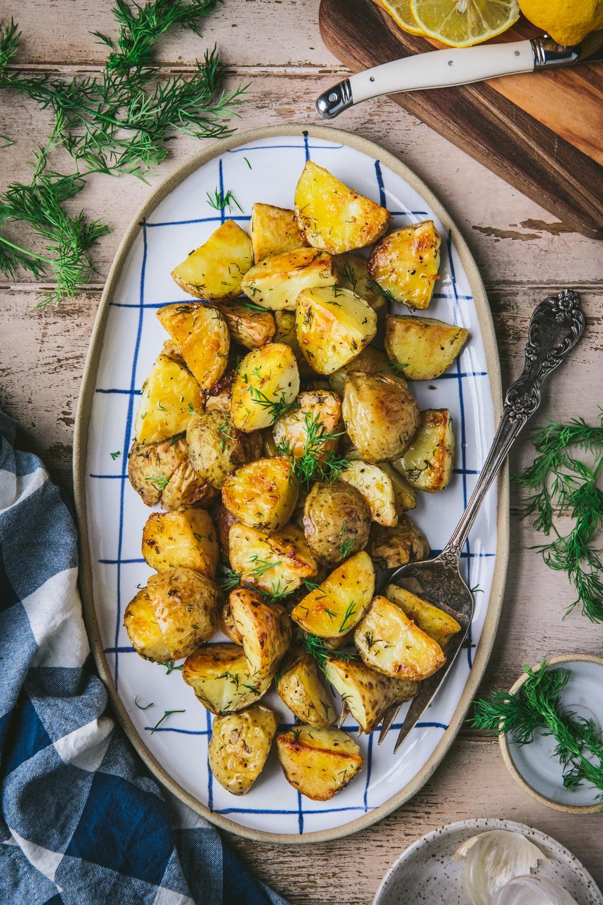 Tray of dill baked potatoes on a wooden table.