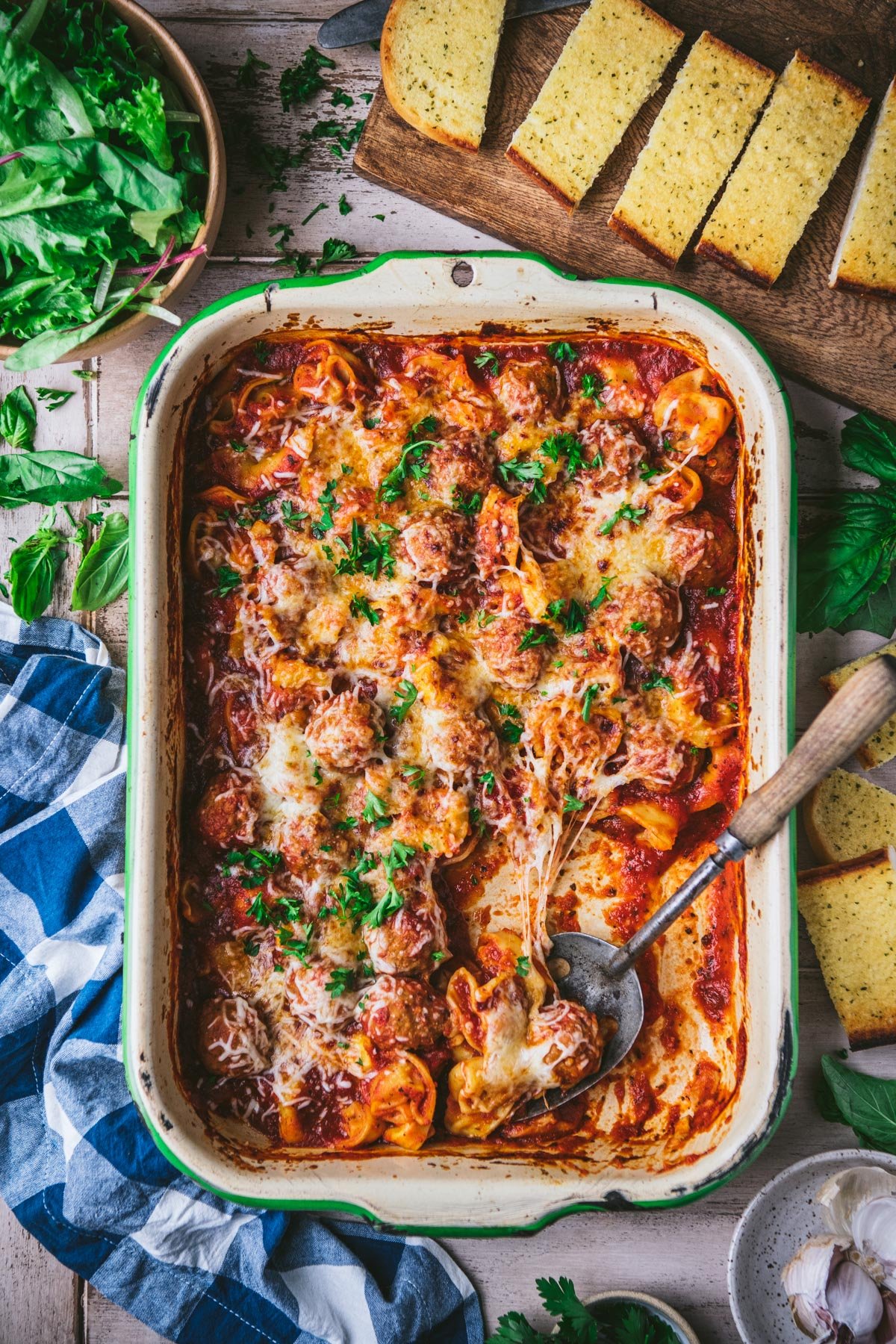 Overhead image of a tortellini and meatball casserole with fresh herbs on top.