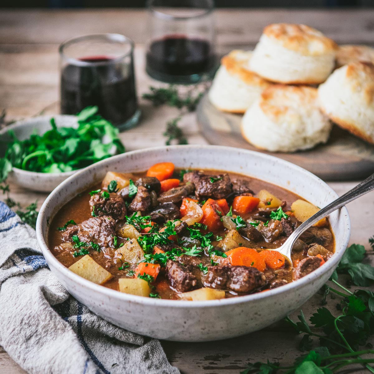 Side shot of beef stew served with biscuits and red wine
