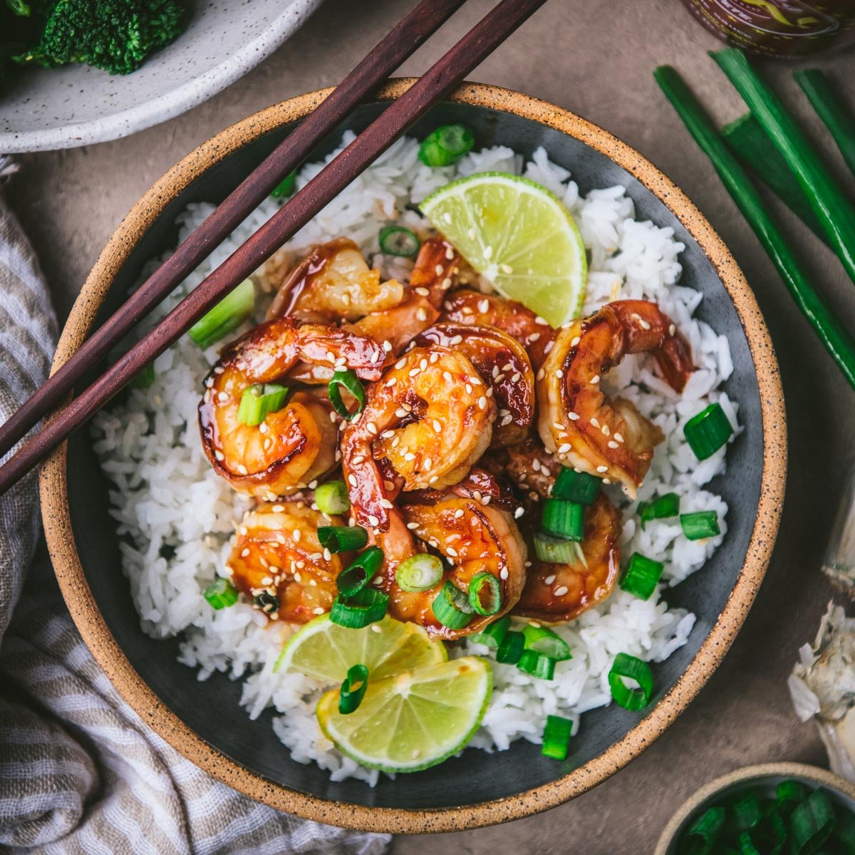 Square overhead image of honey sriracha shrimp with chopsticks on top of the bowl.