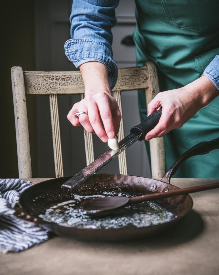 Grating garlic into a pan.