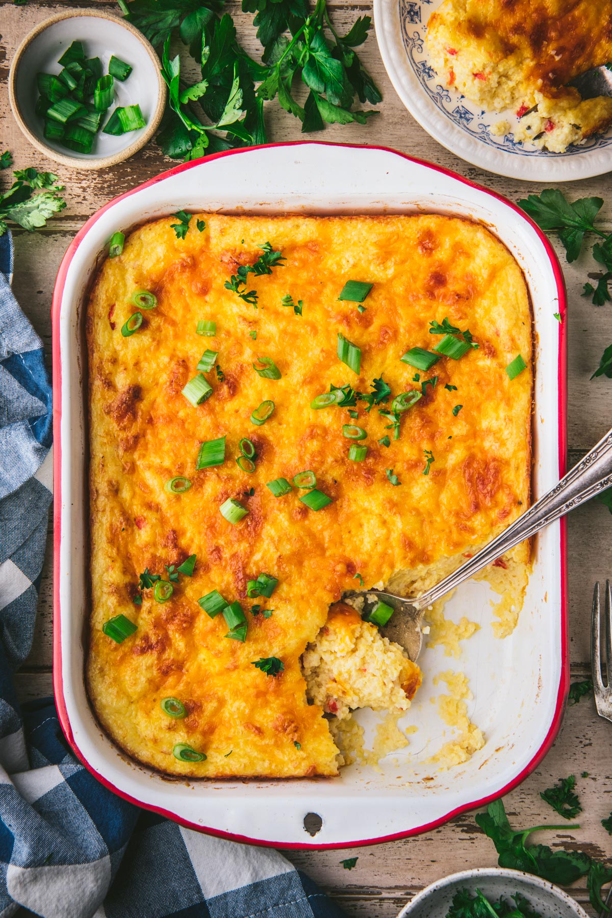Spoon in a cheese grits casserole on a wooden table