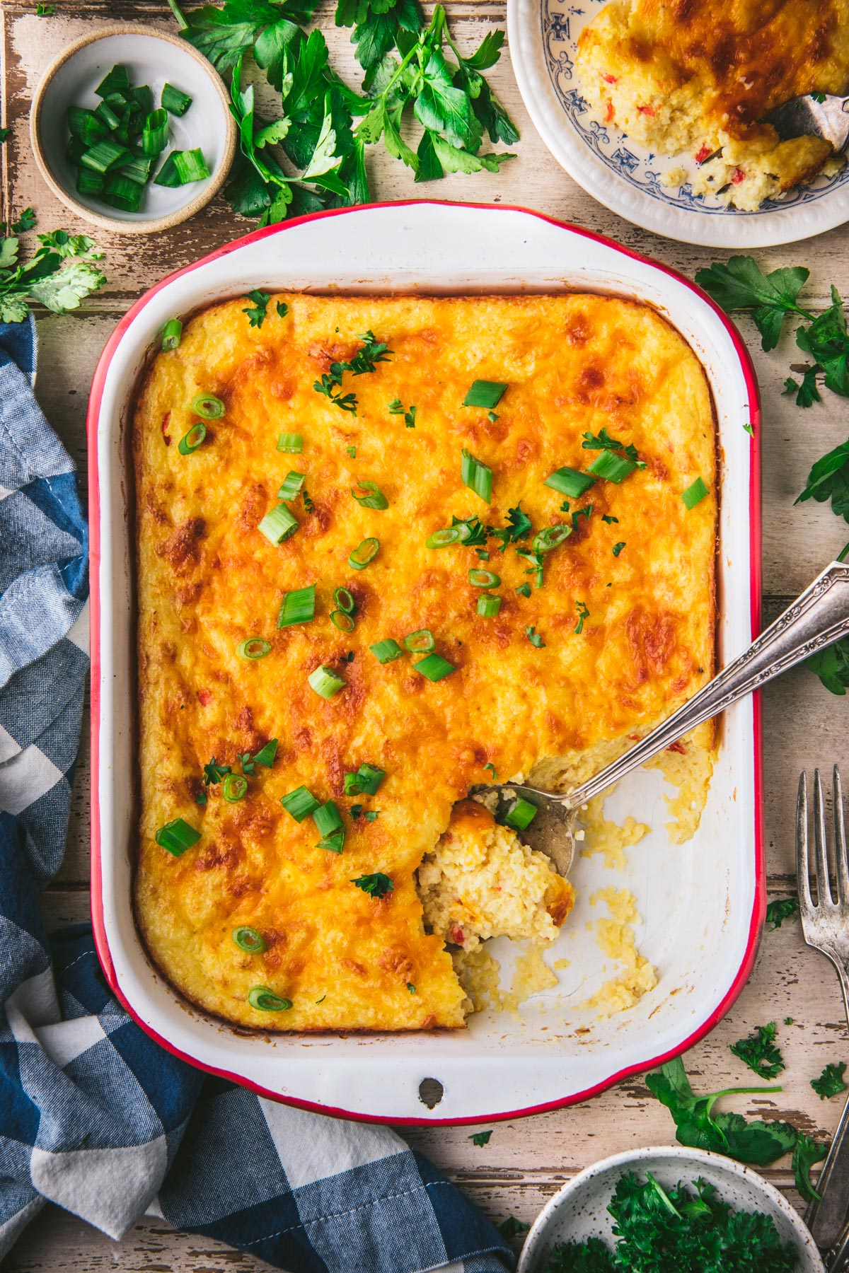 Overhead shot of a pan of baked pimento cheese grits casserole on a wooden table