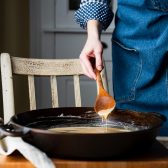 Gold roux on a wooden spoon in a cast iron skillet.