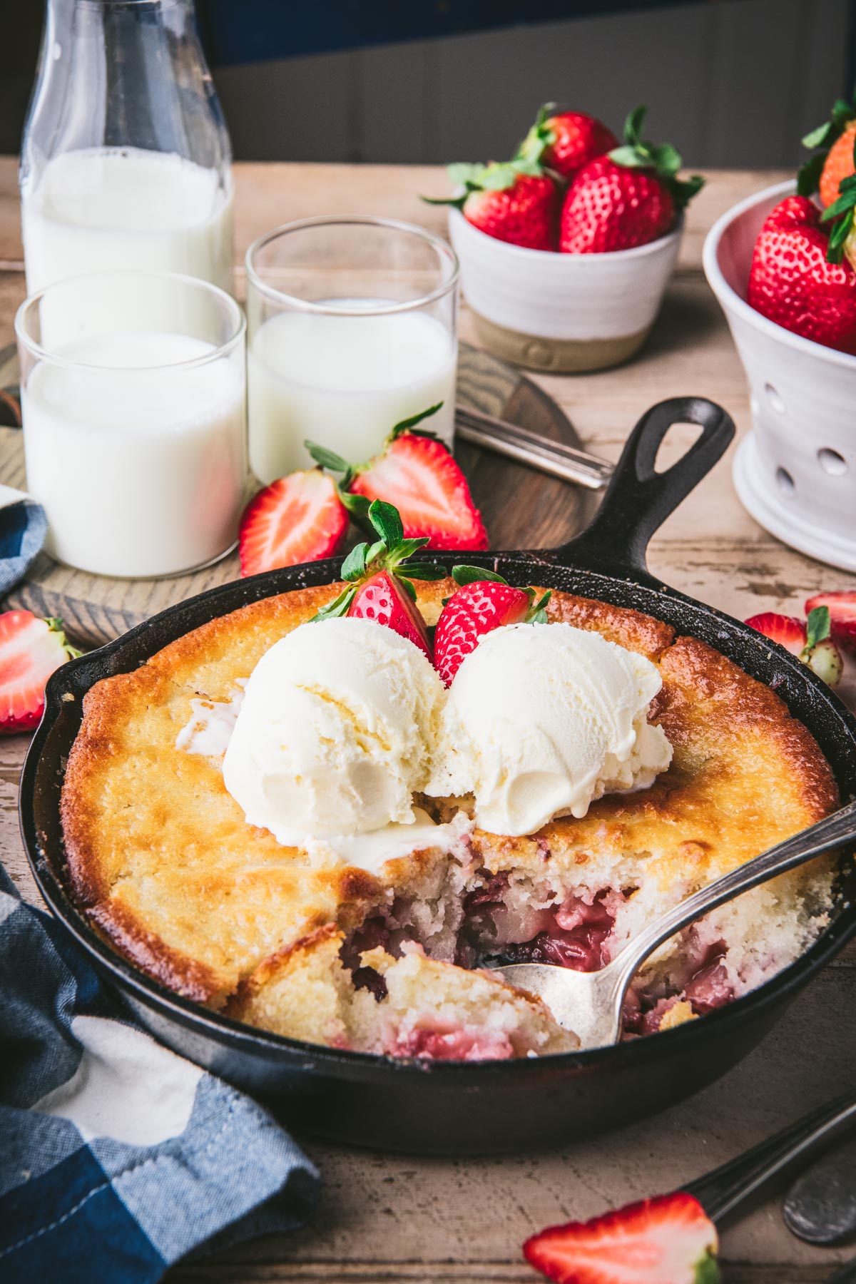 Close up side shot of a serving spoon in a pan of old fashioned strawberry cobbler.