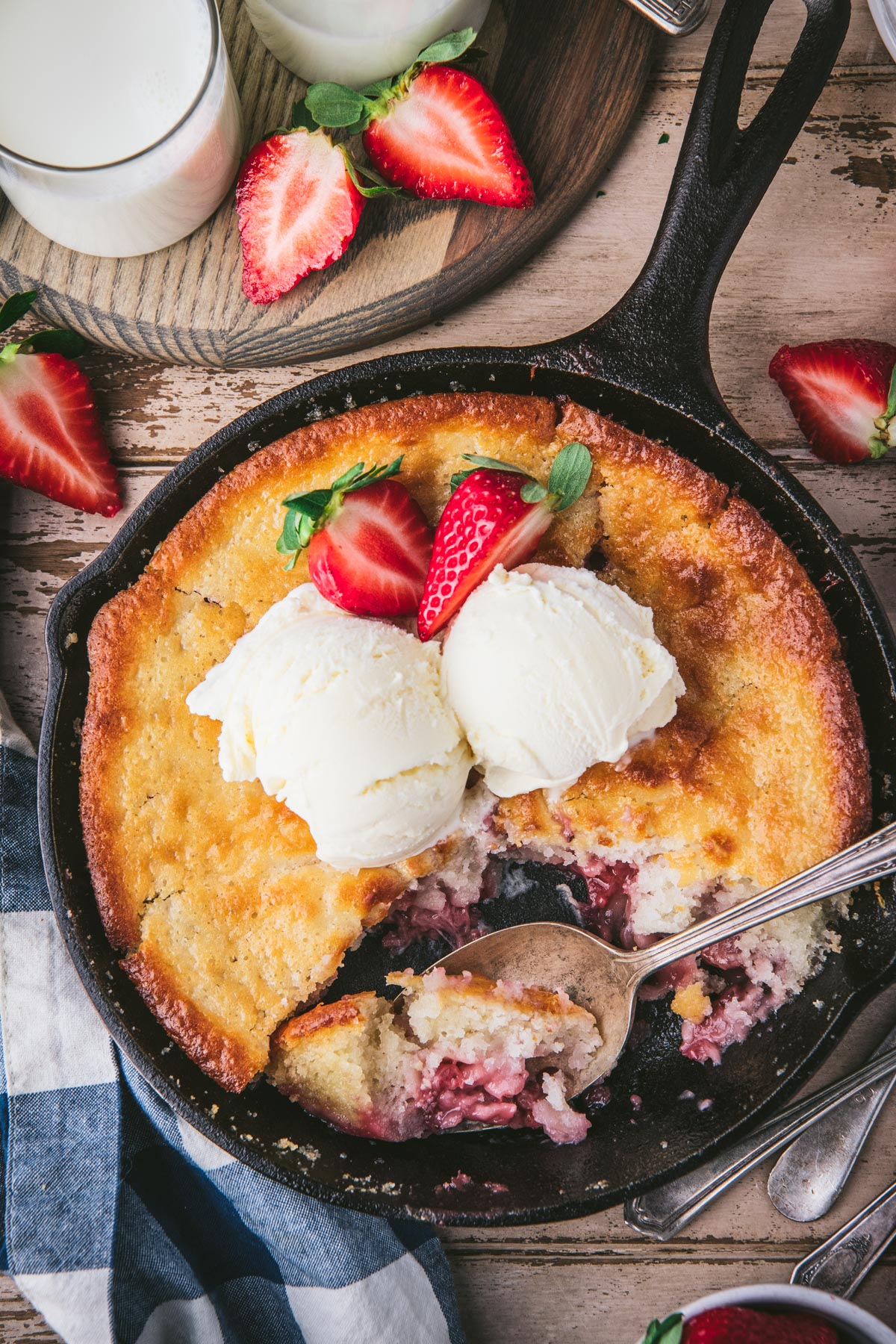 Close overhead shot of a pan of the best strawberry cobbler recipe with two scoops of ice cream on top.