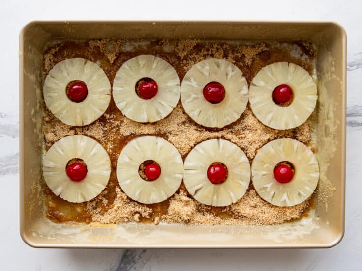 Arranging the pineapples and cherries in a baking pan.