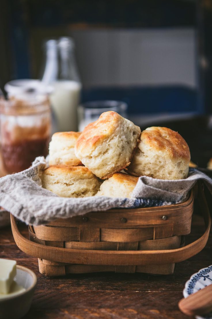 Basket of southern angel biscuits with milk and apple butter in the background