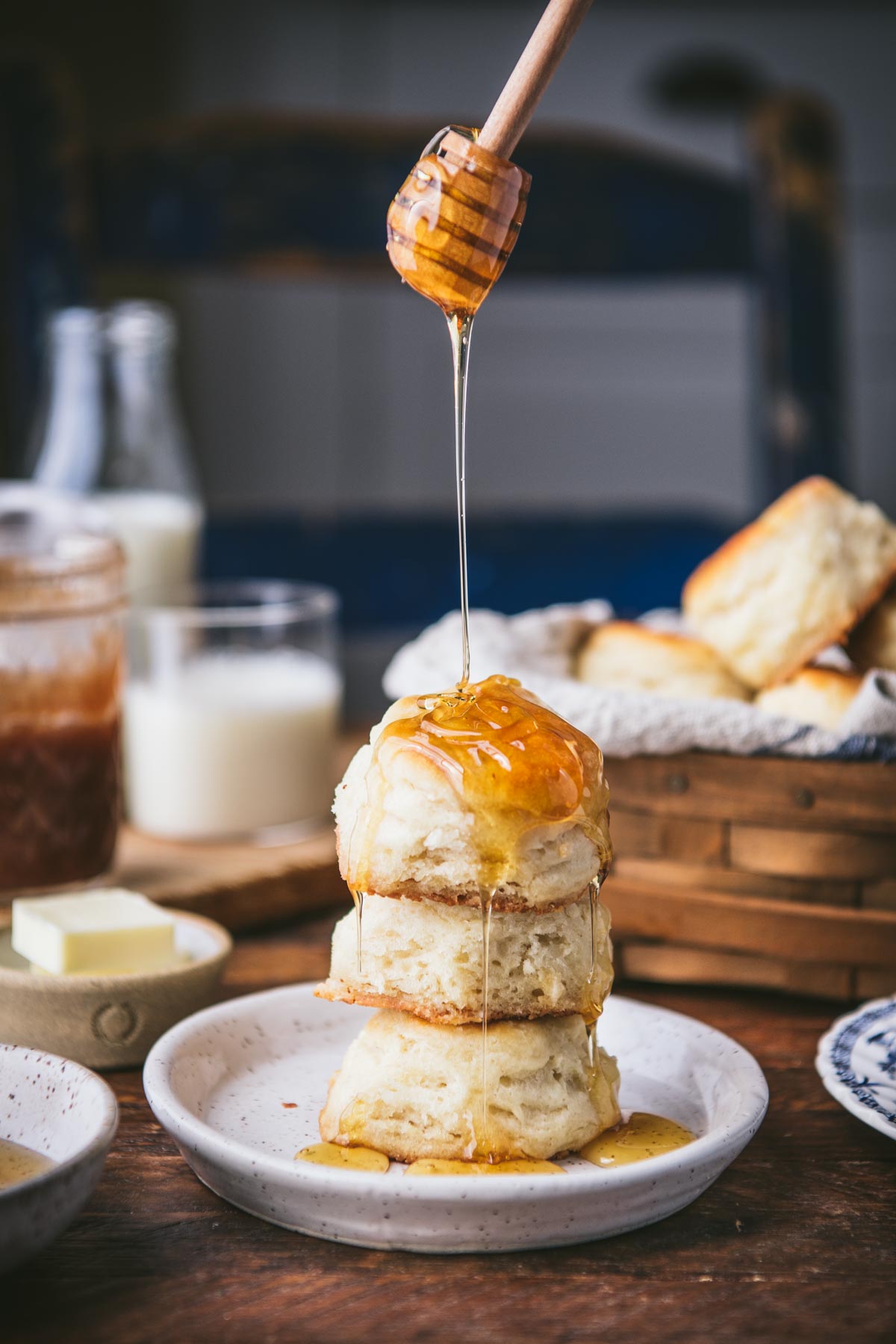 Drizzling honey over a stack of angel biscuits