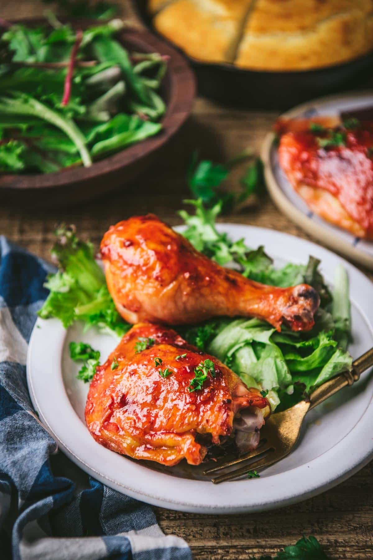Apricot glazed chicken on a dinner table with salad and cornbread.