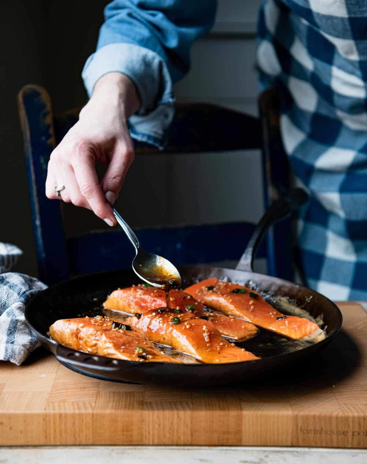 Spooning bourbon glaze for salmon recipe in a skillet