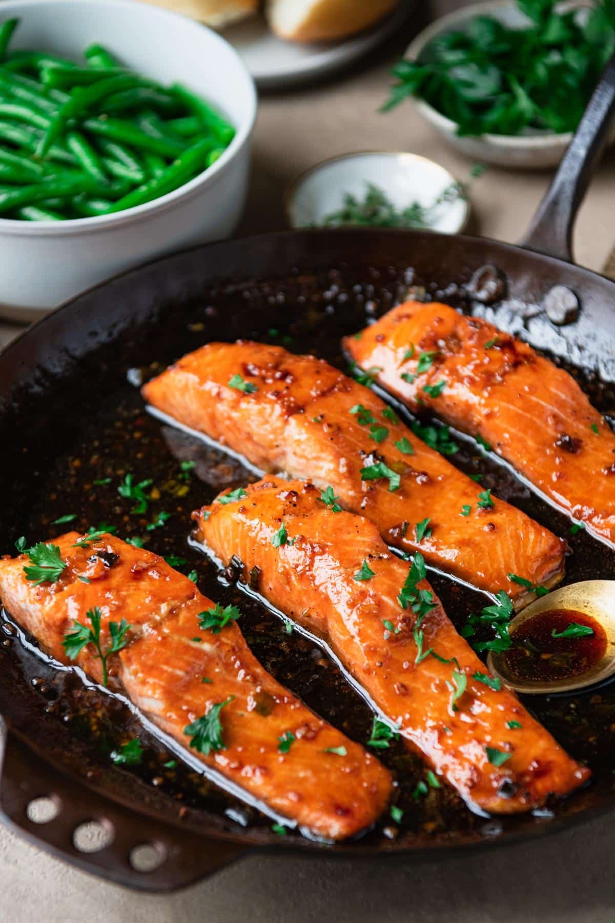 Four pieces of bourbon glazed salmon in a cast iron skillet