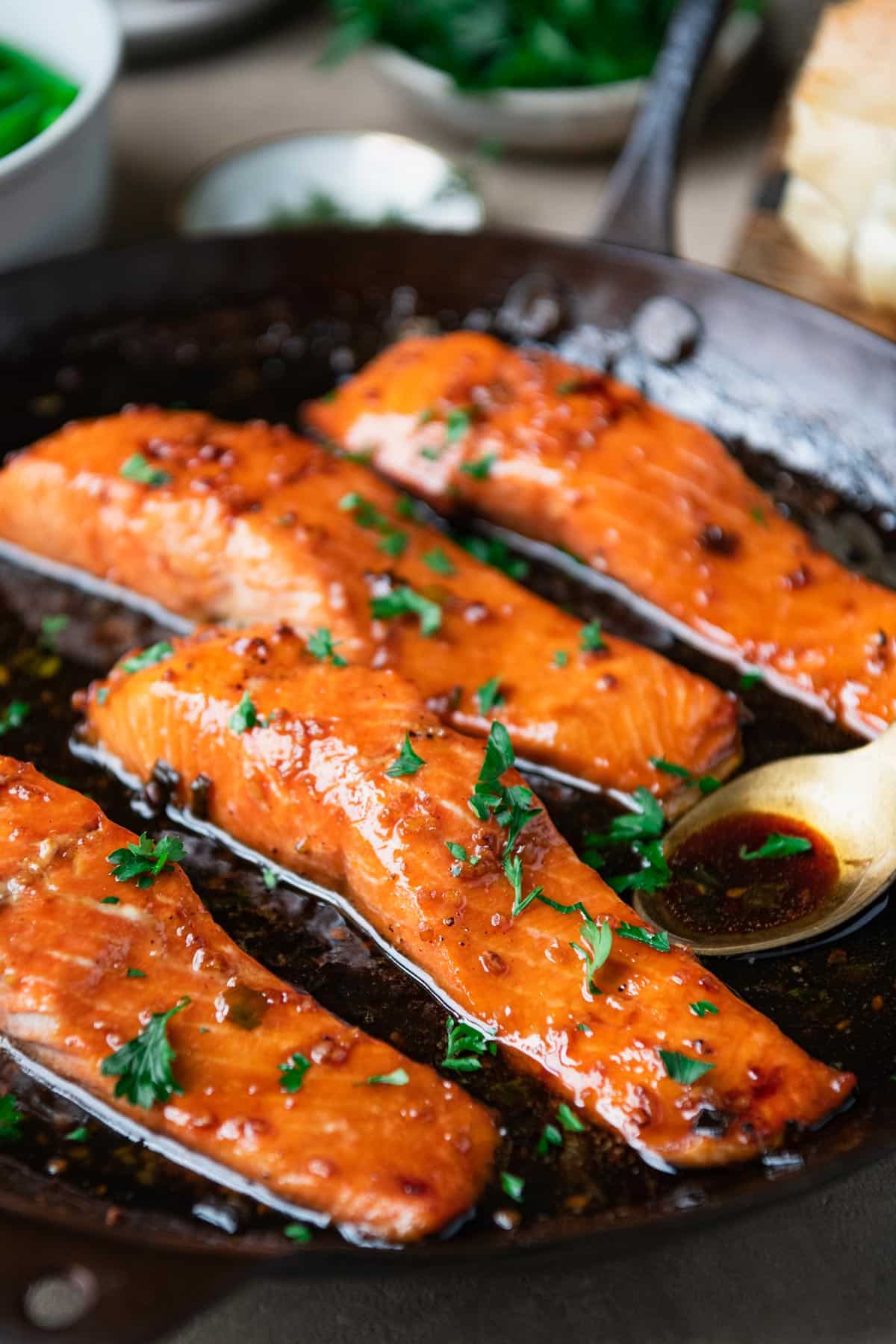 Close up side shot of bourbon glazed salmon in a cast iron skillet