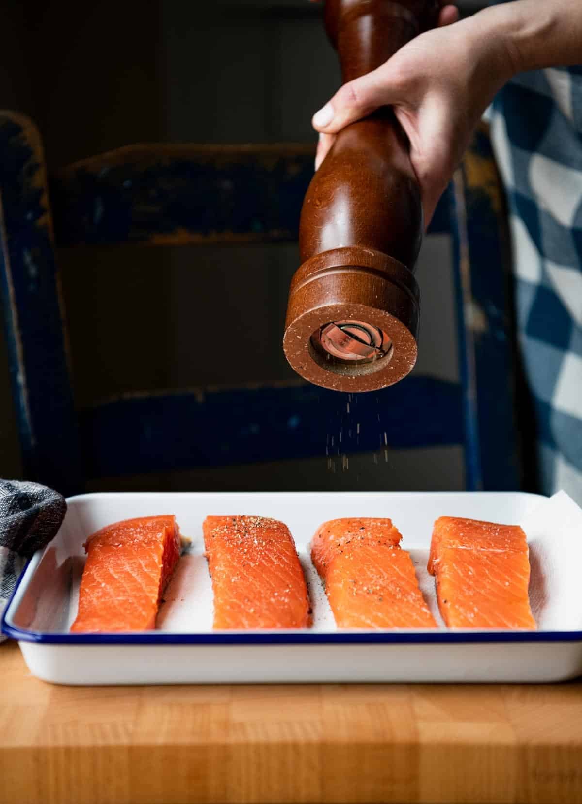 Seasoning salmon with salt and pepper.