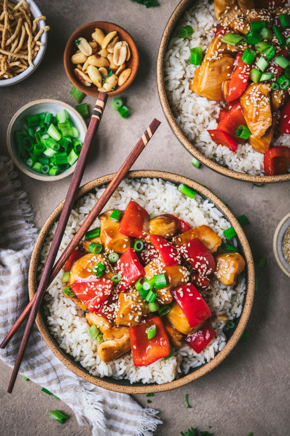 Chicken peppers and rice in a bowl on a dinner table with chopsticks