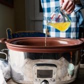 Pouring chicken broth into a slow cooker.