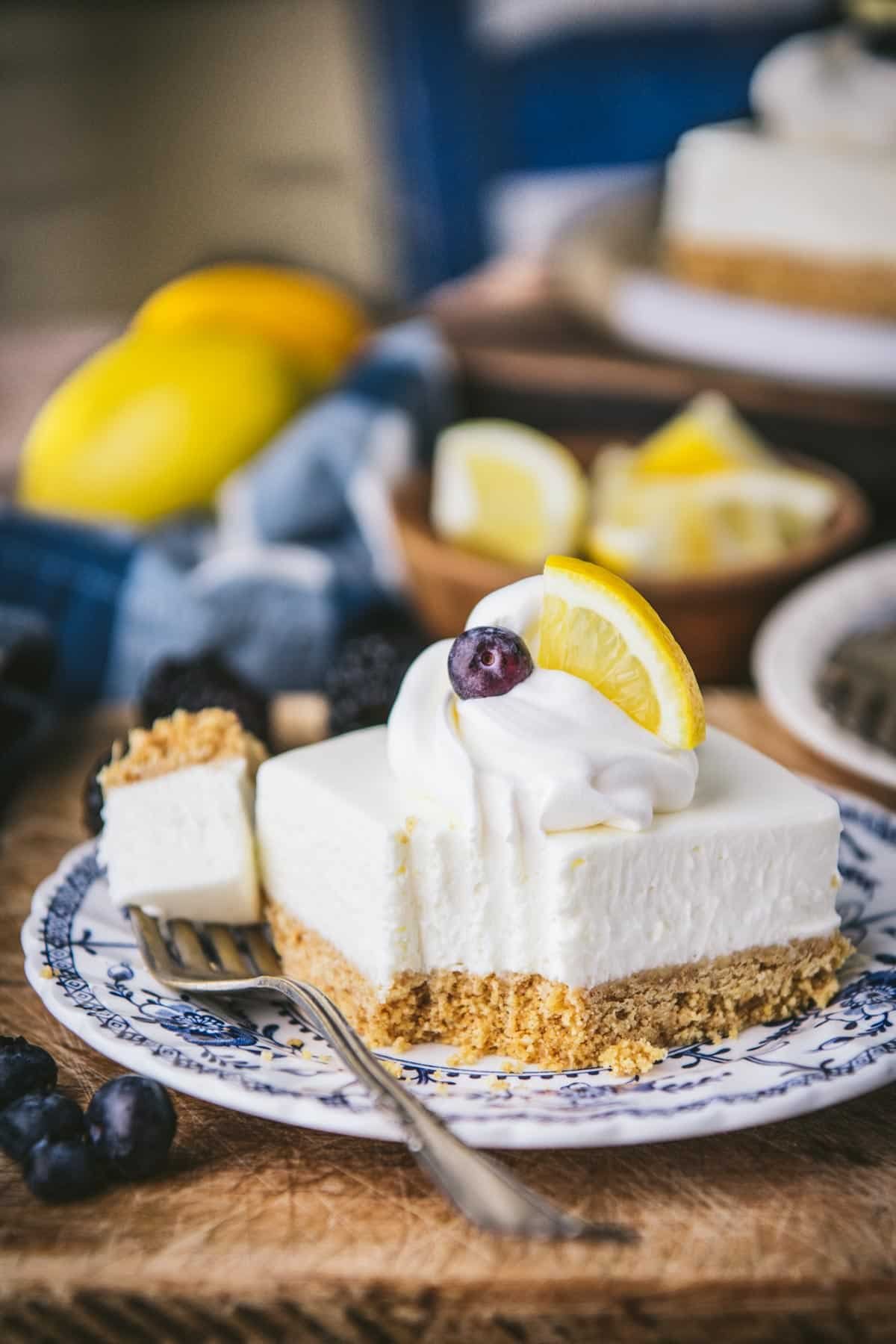 Bite taken out of easy no bake lemon squares with graham cracker crust on a plate.