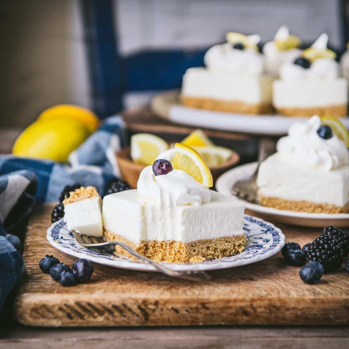 No bake lemon bars with graham cracker crust on a rustic wooden table.