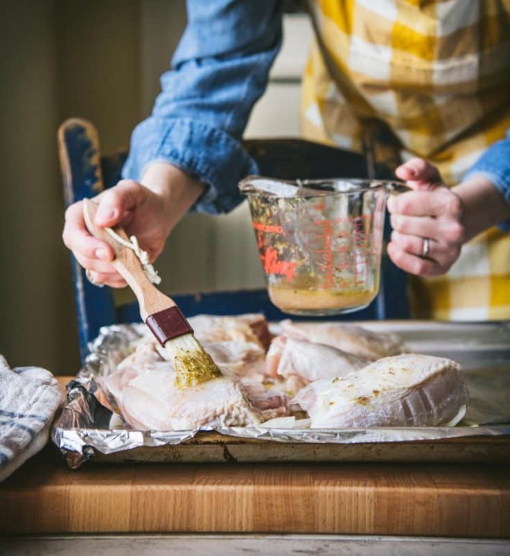 Brushing Greek chicken marinade onto chicken parts.