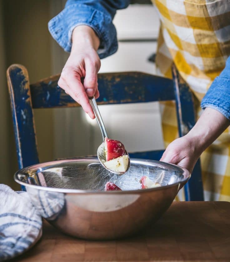 Tossing together red potatoes with marinade.