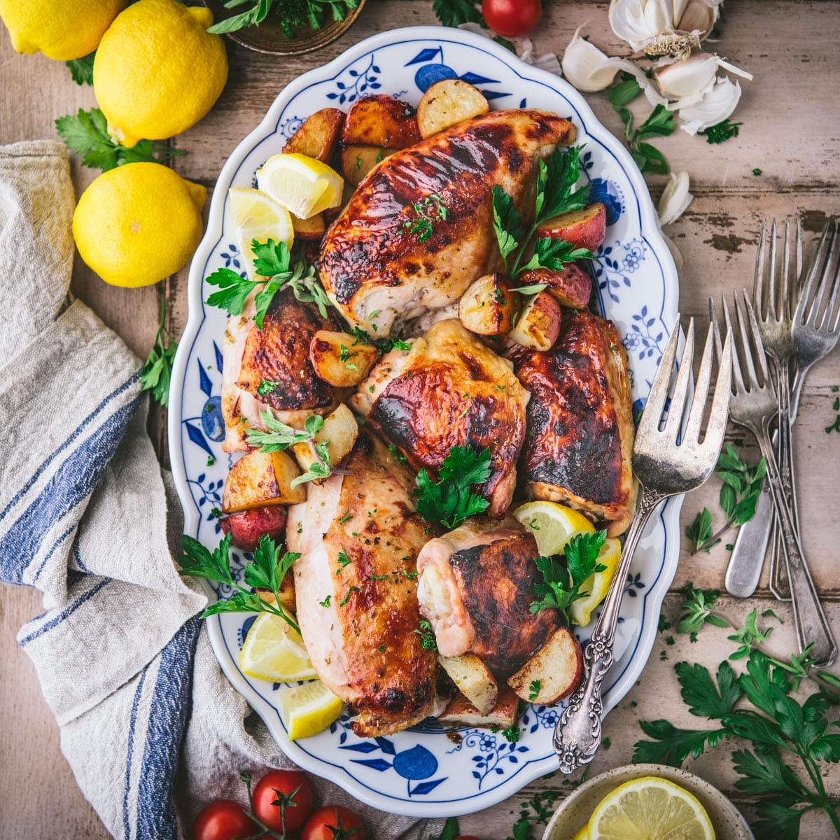 Square overhead shot of one pan greek chicken and potatoes on a wooden table.