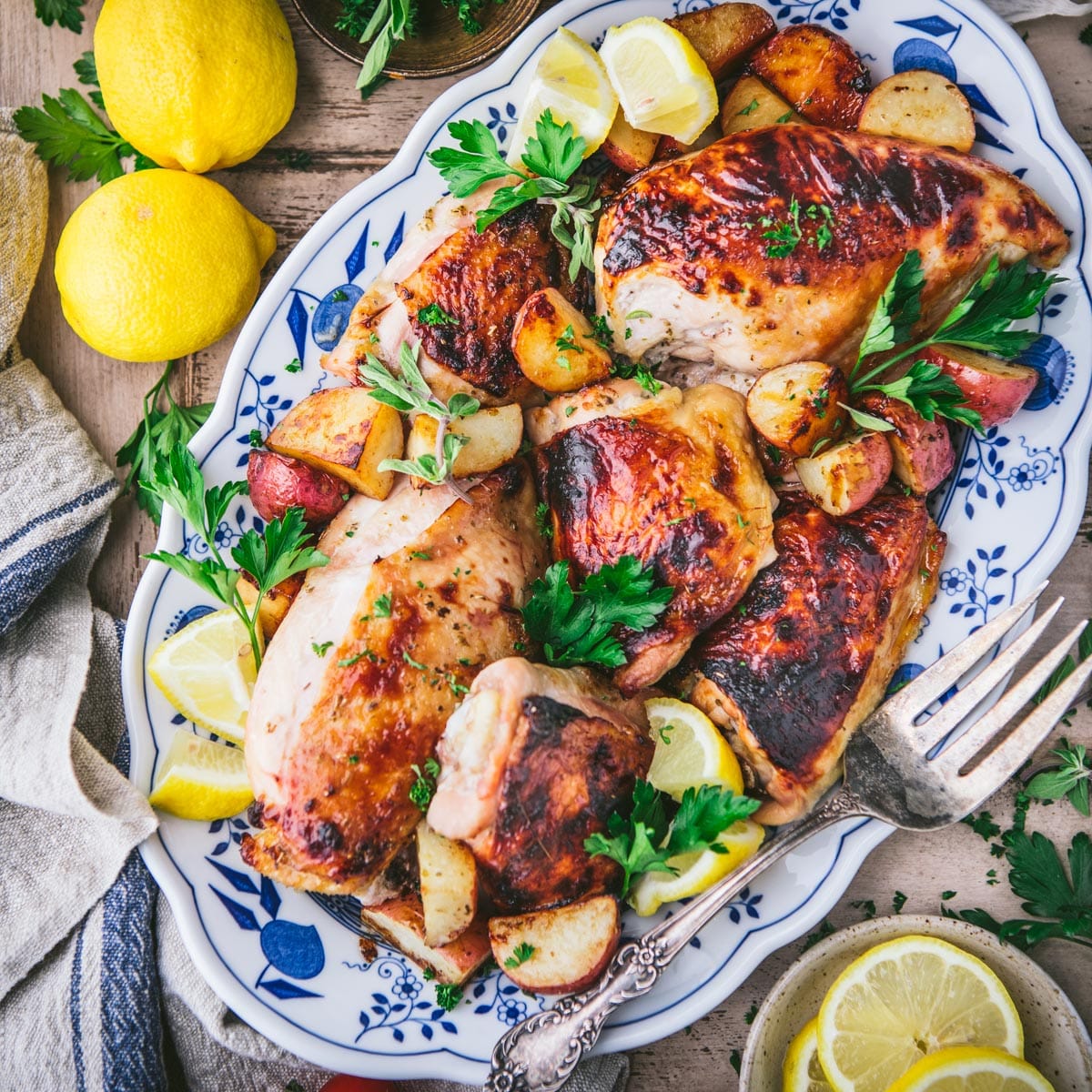 Close overhead image of Greek chicken and potatoes on a blue and white platter.