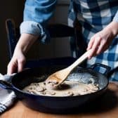 Stirring together mushroom cream sauce in a skillet.
