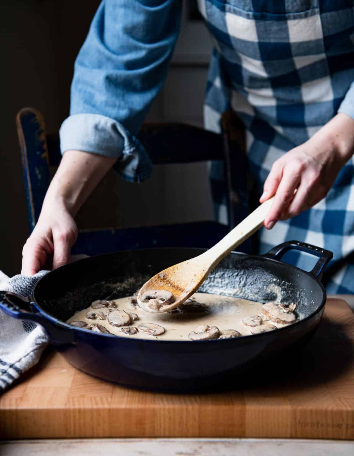 Stirring together mushroom cream sauce in a skillet.