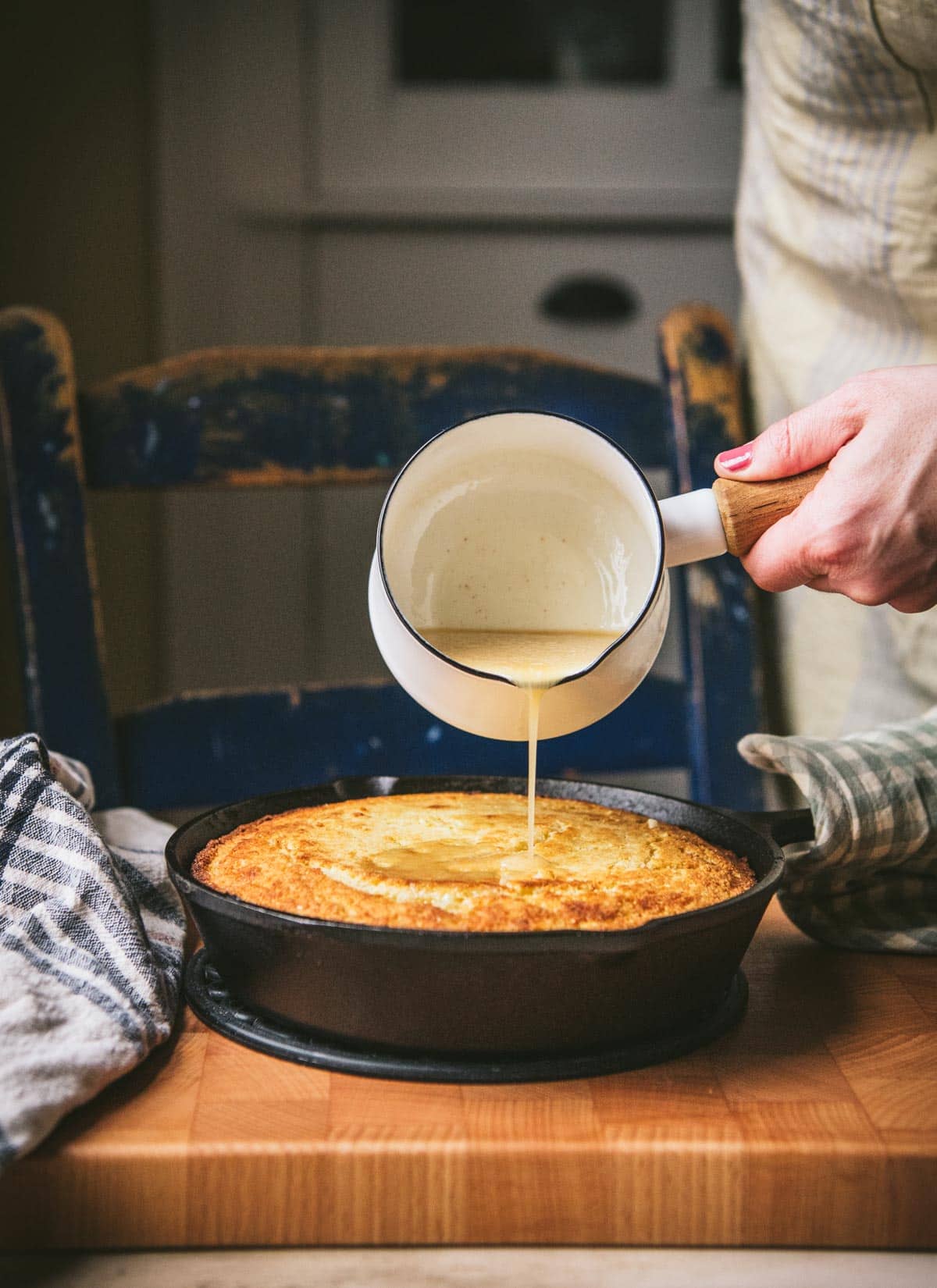 Pouring honey butter over a skillet of cornbread.
