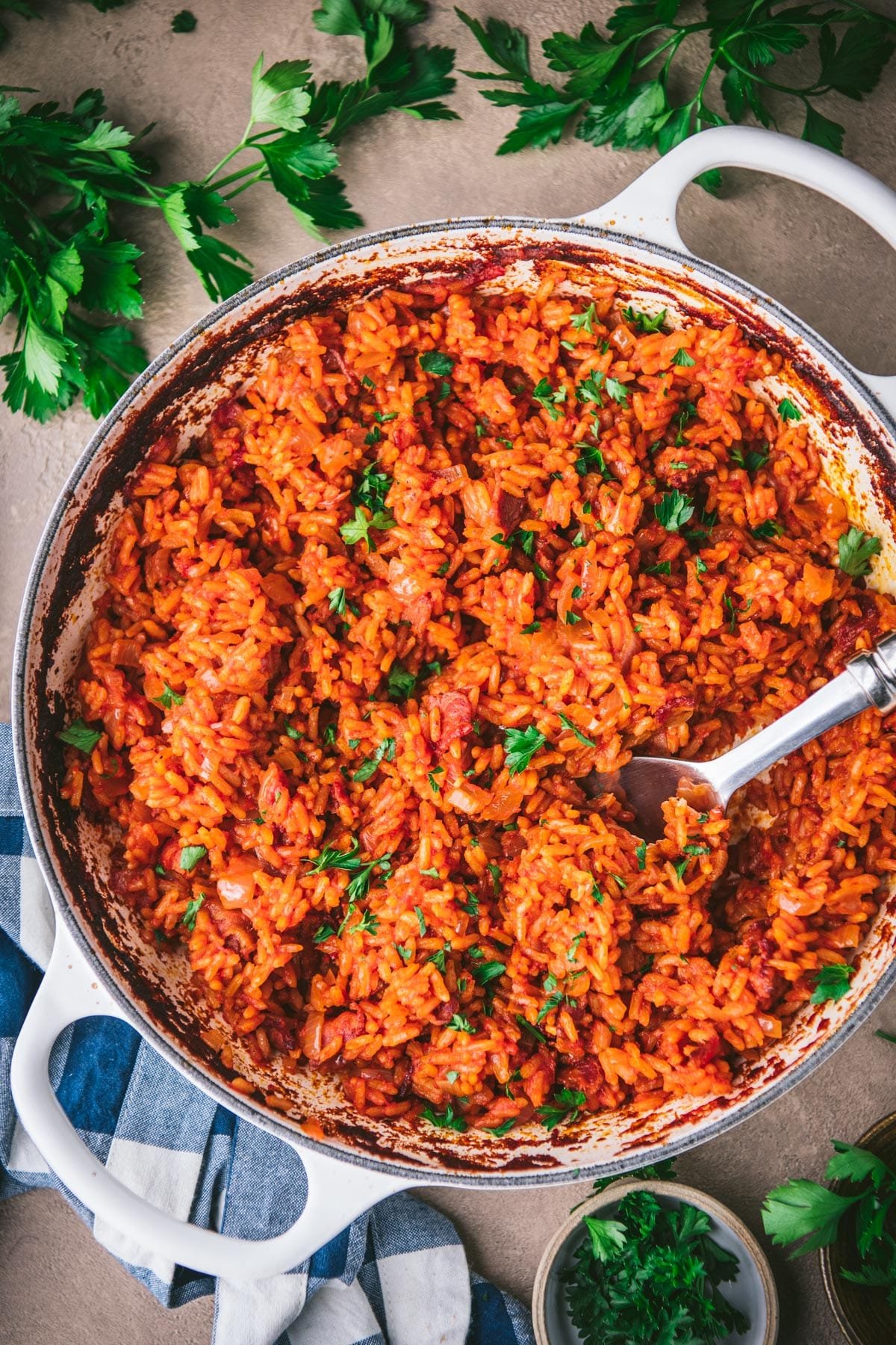 Overhead shot of a skillet of southern red rice on a table with parsley