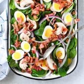Square overhead shot of spinach salad with bacon and hardboiled eggs and poppy seed dressing