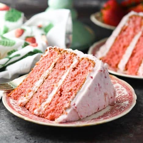 Square side shot of a slice of strawberry cake with cream cheese frosting.