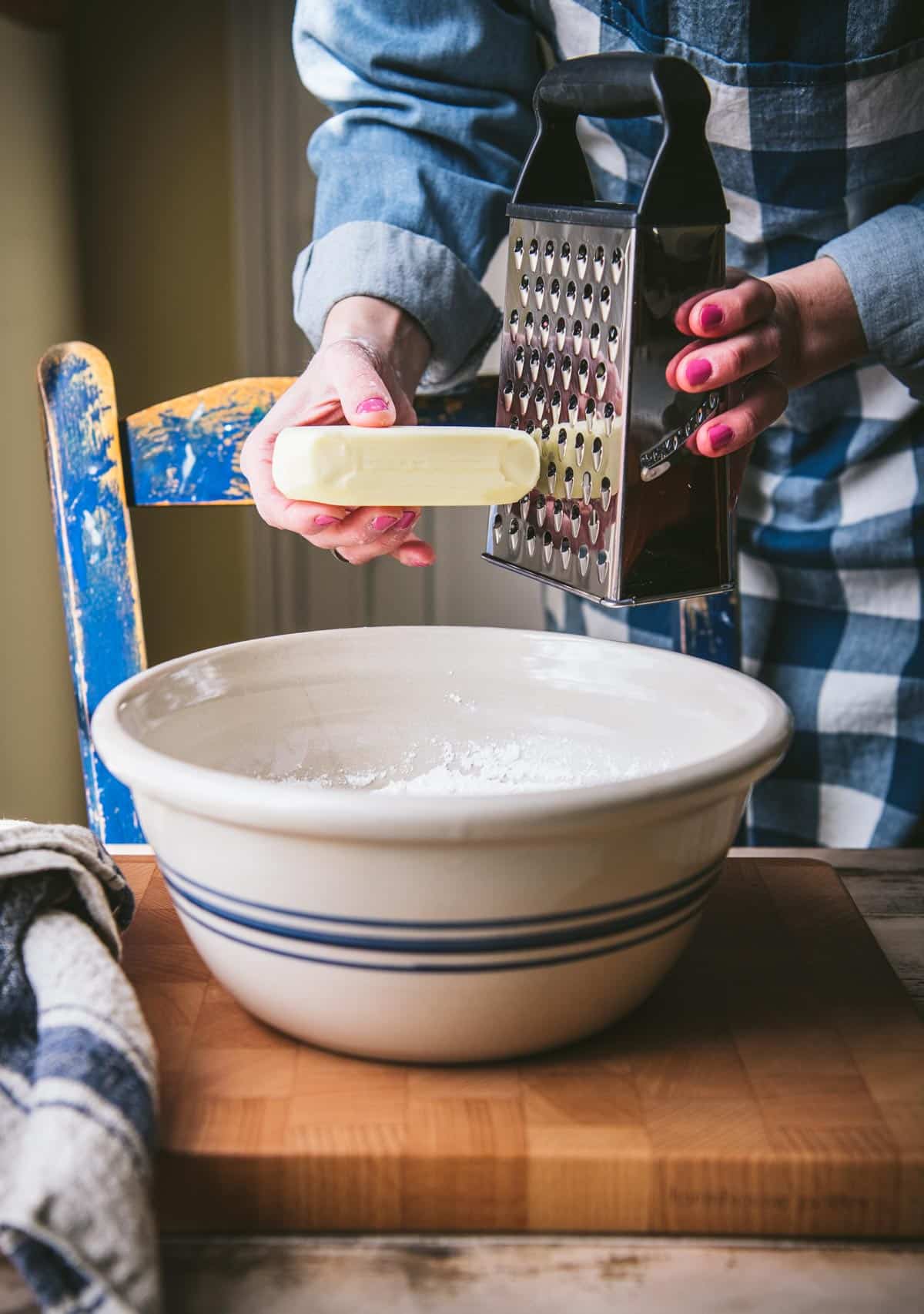 Grating butter into a mixing bowl.