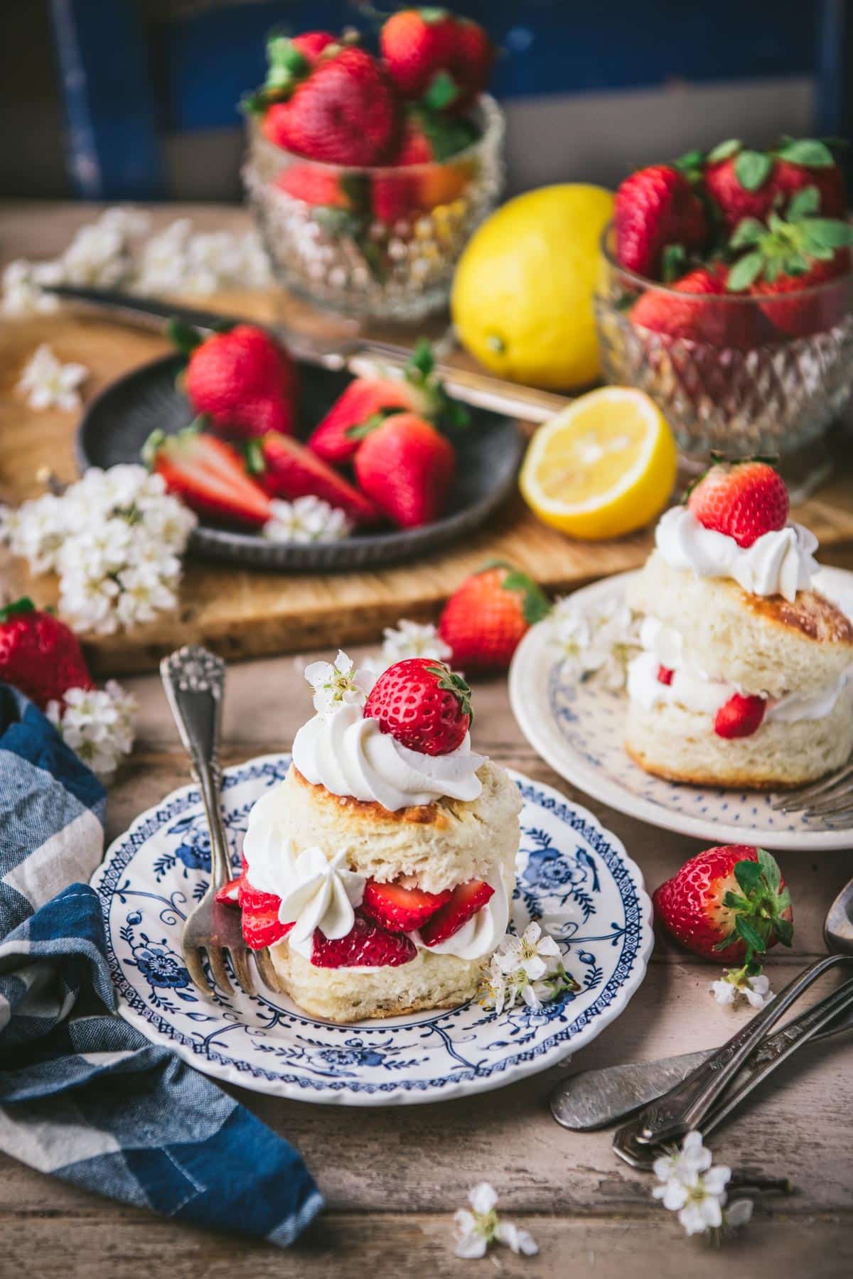 Two plates of strawberry shortcake biscuits on a wooden table.