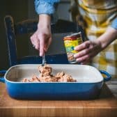 Spreading refried beans in a blue casserole dish