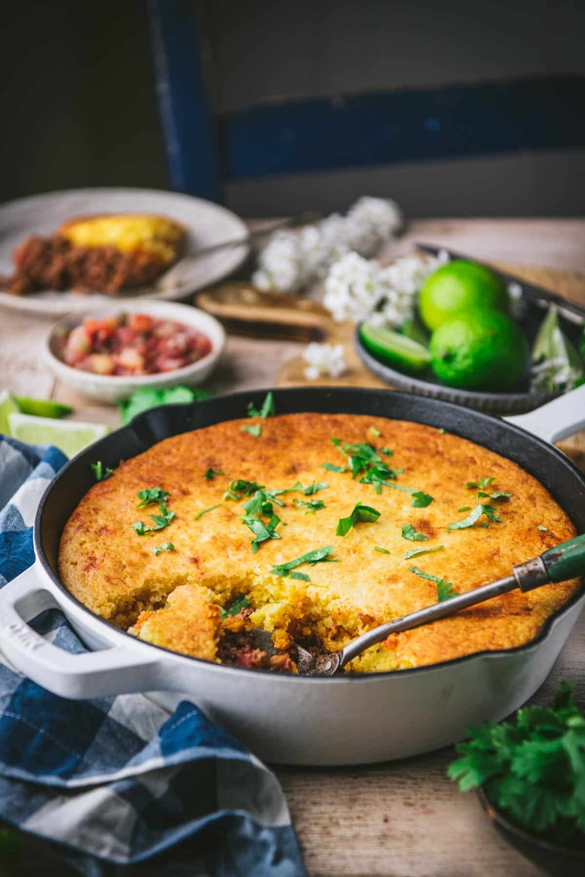Side shot of a skillet of tamale pie on a dinner table.