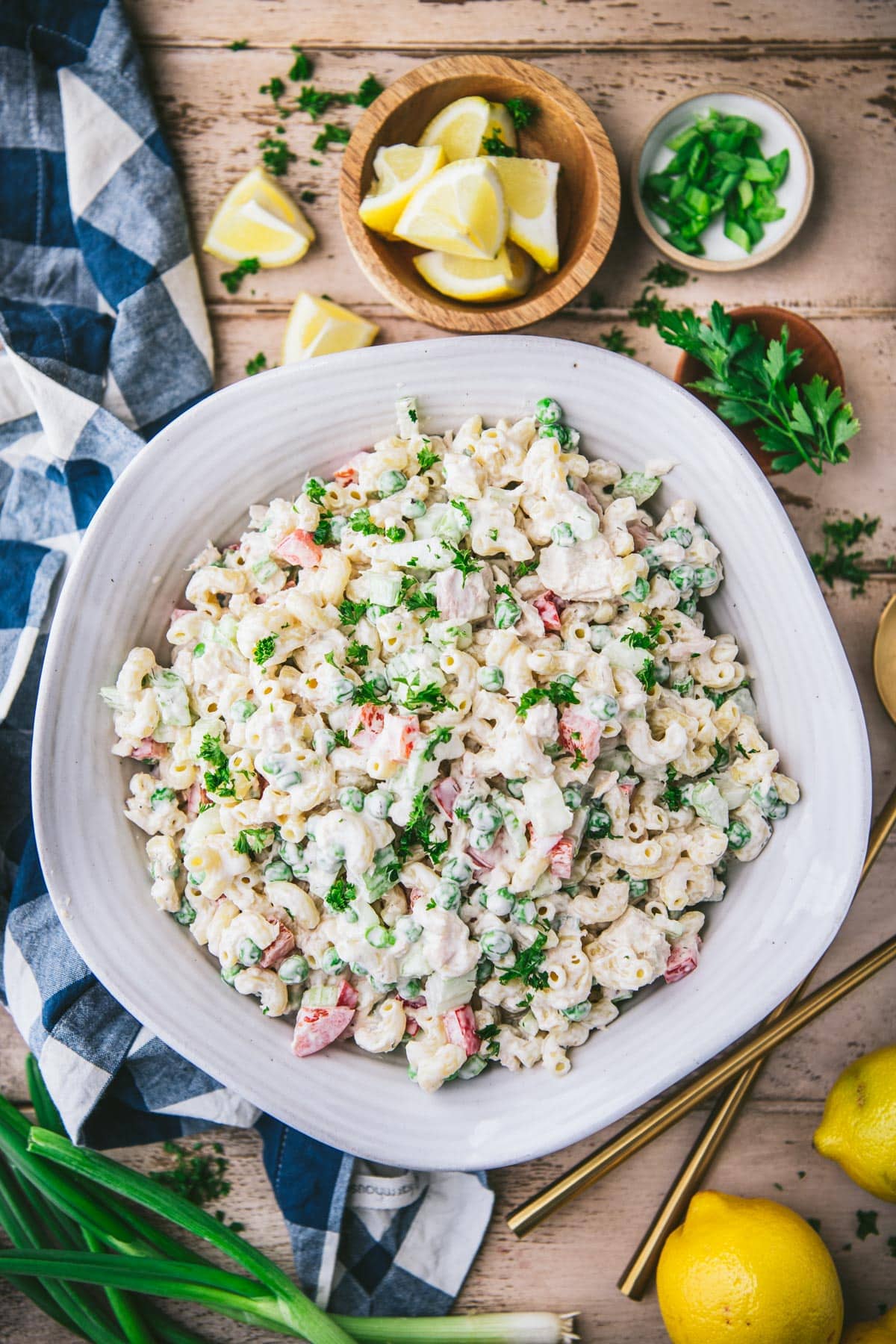 Overhead shot of a bowl of the best tuna pasta salad recipe with lemons and herbs on the table.