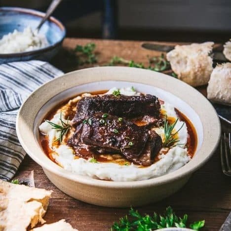 Square side shot of red wine braised beef short ribs with mashed potatoes in a bowl.