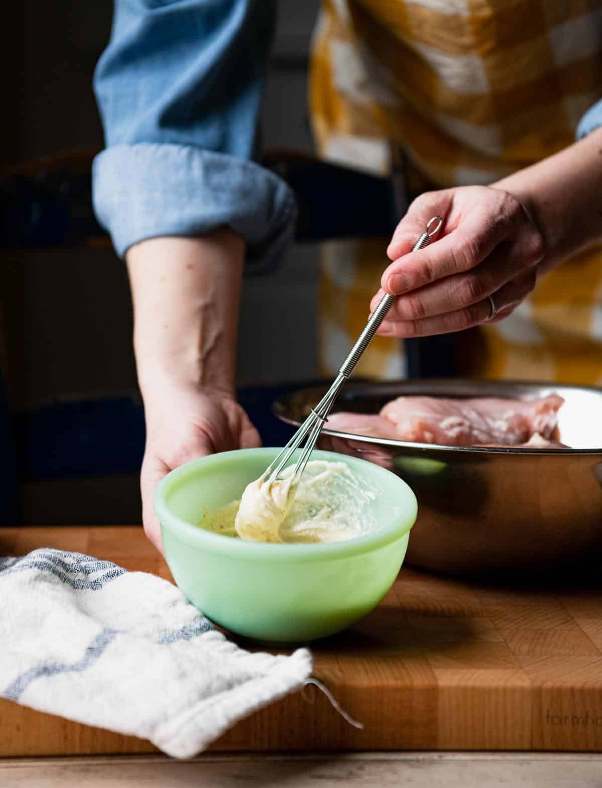 Whisking together mayo mixture in a small green bowl.