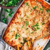 Overhead image of dump and bake chicken parm casserole on a green table with a side salad and bread.