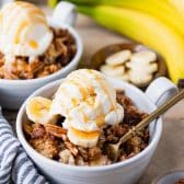Side shot of two bowls of easy banana dump cake with ice cream on top.