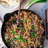 Wooden spoon in a skillet of the best ground beef stir fry recipe.