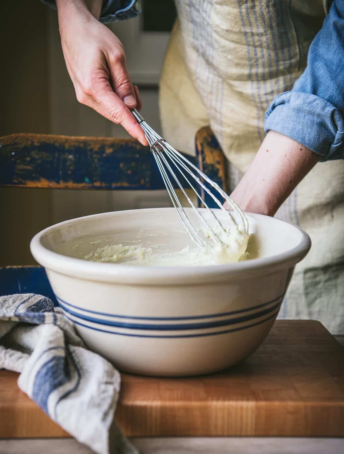 Whisking together cornbread with sour cream and creamed corn.