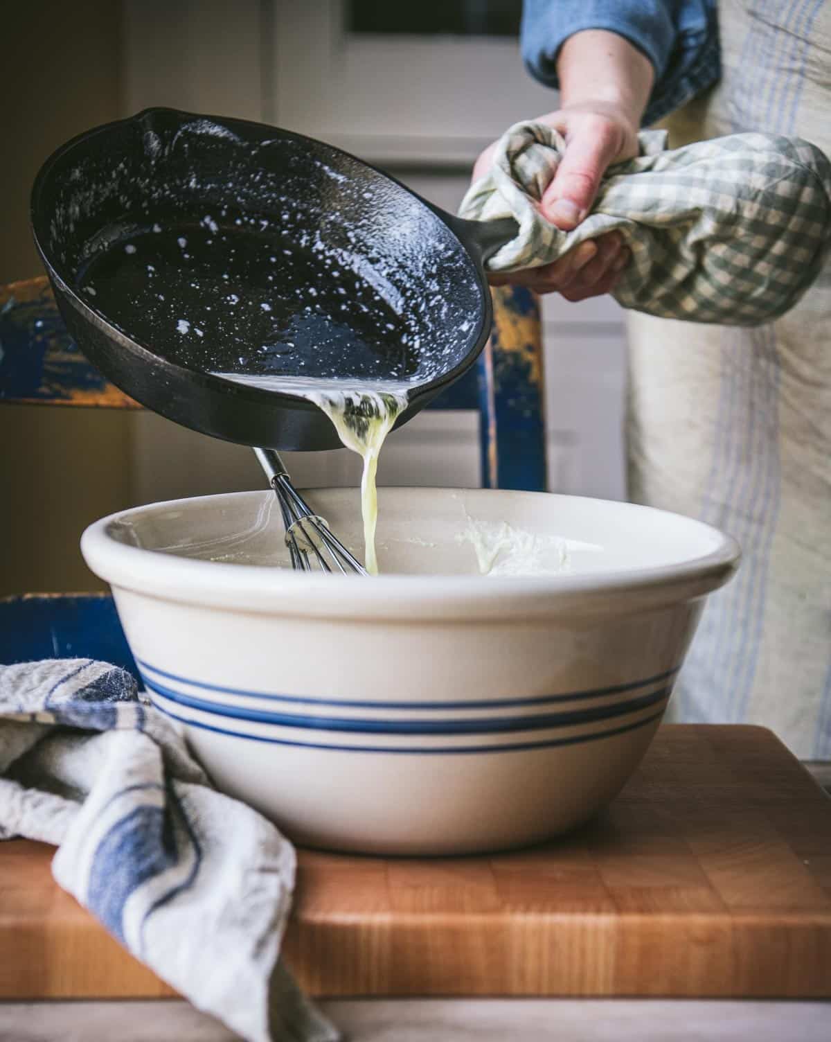 Pouring melted butter into a big mixing bowl.