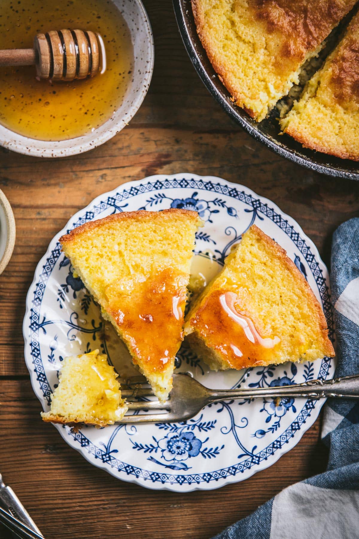 Overhead image of two slices of sour cream cornbread on a plate with a fork.