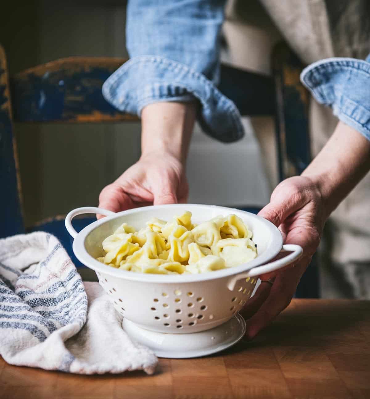 Draining tortellini pasta in a colander.
