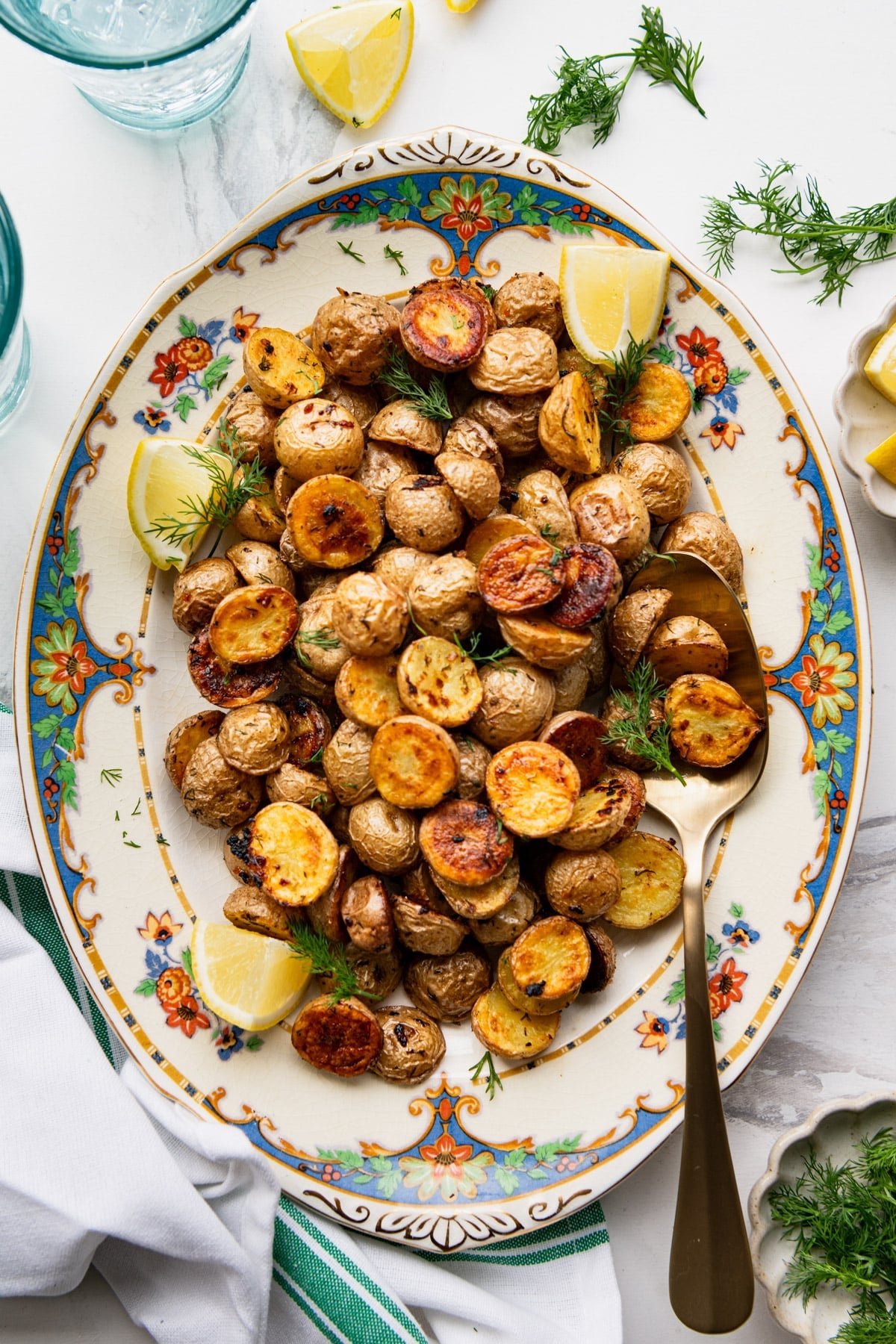 Overhead shot of a platter of roasted potatoes with dill.