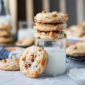 Square side shot of salted butterscotch cookies with pecans on top of a glass of milk.